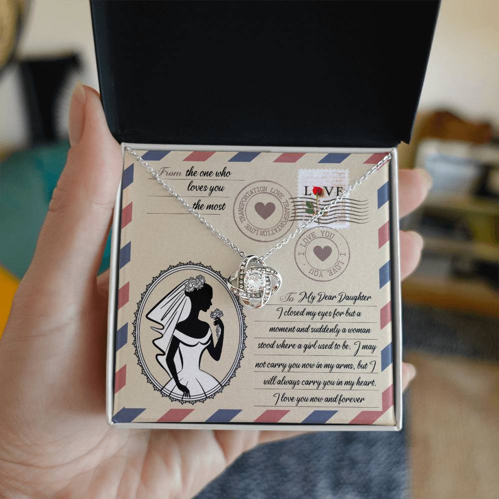 A To Daughter Wedding, In My Arms - Love Knot Necklace with a heart-shaped pendant on a card with a vintage design, featuring cubic zirconia crystals, a silhouette of a woman in a wedding gown, and a heartfelt message addressed to a daughter.