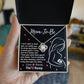 A hand holds a gift box containing a personalized To Mama To Be, The Best Mommy - Love Knot Necklace with a pendant and a message for an expectant mother from "the bump" by ShineOn Fulfillment.