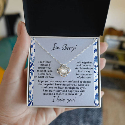 The "Sorry-Through My Eyes - Love Knot Necklace," adorned with cubic zirconia crystals and a white gold finish, is presented on a card featuring a heartfelt apology message, expressing regret for causing pain and seeking forgiveness.