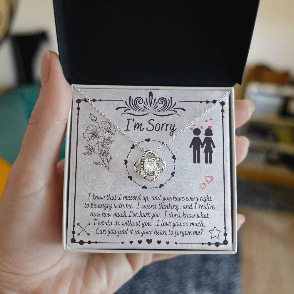 The "Sorry-I Would Do - Love Knot Necklace" is a personalized gift box that includes an apology message and a Love Knot Necklace adorned with cubic zirconia crystals. The box features the phrase "I'm Sorry" above illustrations of flowers and a couple, expressing regret for a mistake and seeking forgiveness.