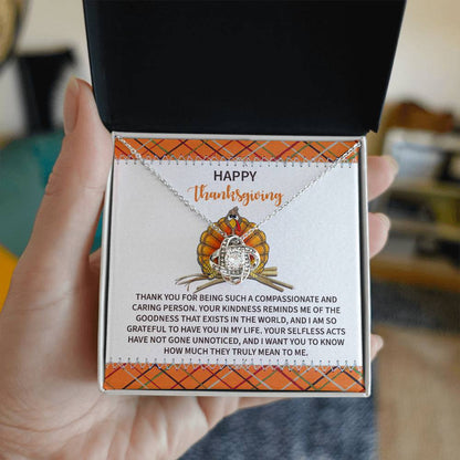 A hand holding an open box reveals the stunning "Thanksgiving-In My Life - Love Knot Necklace" adorned with cubic zirconia crystals. The box features a Thanksgiving-themed message and a charming pumpkin illustration, making it the perfect personalized gift for the occasion.