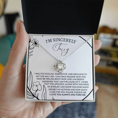 The Sorry-Care For You - Love Knot Necklace features a pendant with intertwined loops adorned with sparkling cubic zirconia crystals. It is elegantly displayed on a card that conveys an apology message, reading "I'm sincerely sorry," expressing deep regret and love.