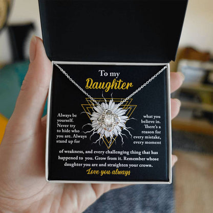 A personalized gift, this "To Daughter, Be Yourself - Love Knot Necklace" features a pendant encrusted with cubic zirconia crystals, nestled in a gift box. The box lid displays a heartfelt message addressed to "My Daughter," showcasing motivational and supportive text alongside a sunflower graphic.