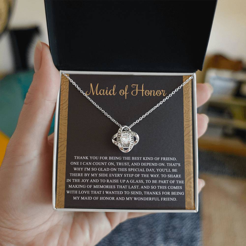 The "To Maid of Honor, Kind Of Friend - Love Knot Necklace" features an intertwined knot design adorned with cubic zirconia crystals on a background that reads "Maid of Honor," followed by a heartfelt thank you message to the maid of honor.