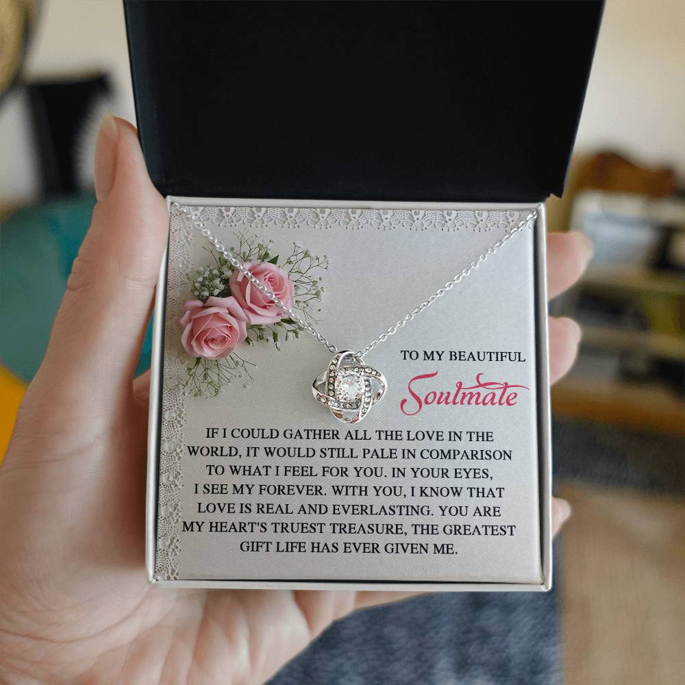 A hand displays the Soulmate-Given Me - Love Knot Necklace, decorated with cubic zirconia crystals. The box features pink roses and a touching message for a "Beautiful Soulmate," ideal as a personalized gift.