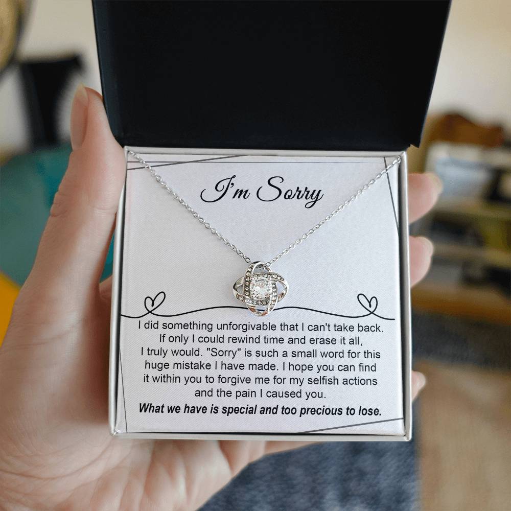 The Sorry-Breaking My Heart - Love Knot Necklace, featuring a gold finish and embellished with sparkling cubic zirconia crystals, is presented on a heartfelt message card that expresses deep regret for a mistake and seeks forgiveness.