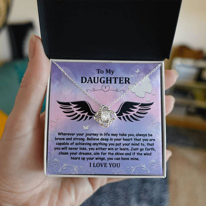 The "To Daughter, Brave And Strong - Love Knot Necklace" features a gold finish and a Cubic Zirconia pendant, beautifully displayed in a box. The box contains a heartfelt message titled "To My Daughter," encouraging bravery, strength, and the pursuit of dreams, and concludes with the words "I LOVE YOU.