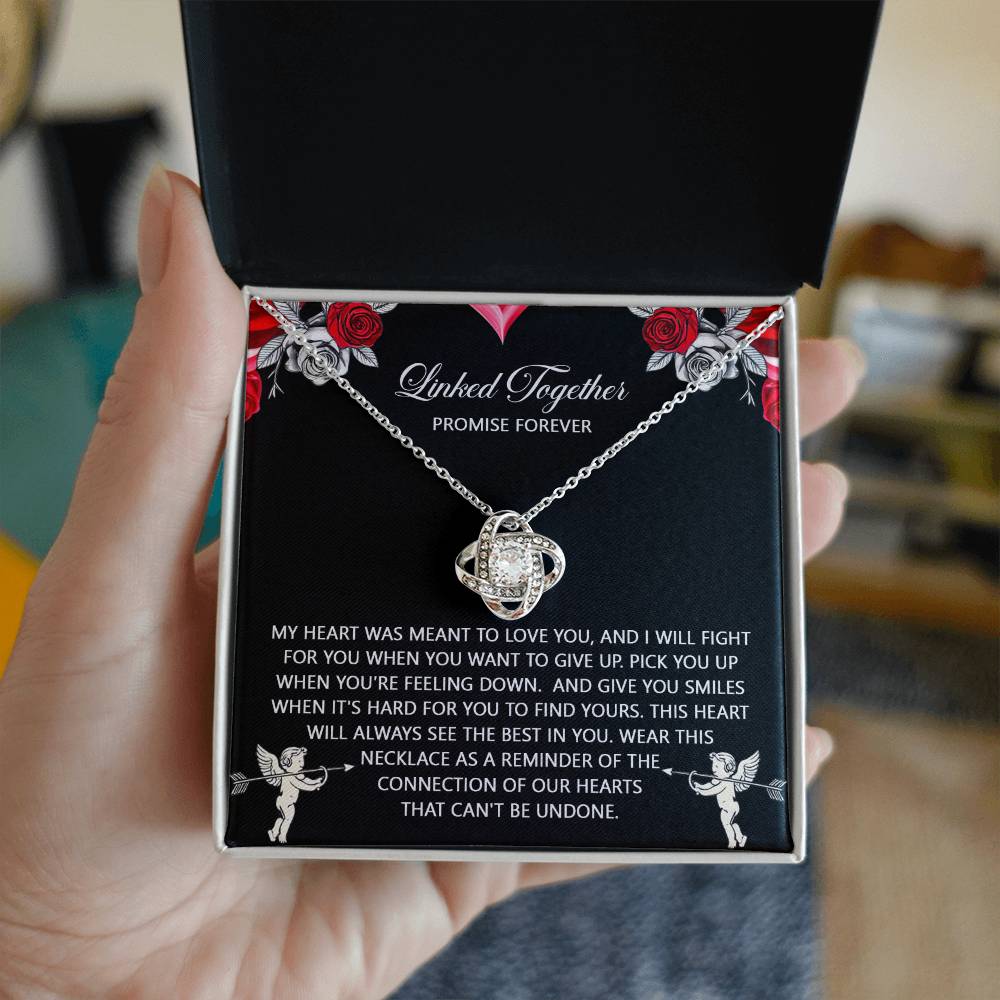 A person holds an open box with the "Soulmate-To Find Yours - Love Knot Necklace," featuring a heart-shaped pendant with cubic zirconia. Accompanied by a romantic message about love and connection, it makes the perfect unique gift.