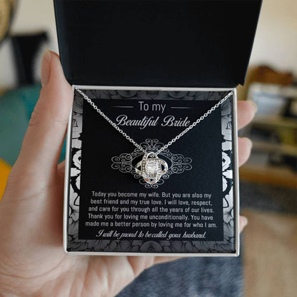 The "To Bride, My True Love - Love Knot Necklace" with a diamond pendant is displayed in a black and white box adorned with a floral pattern. The box, featuring cubic zirconia crystals, includes a heartfelt message addressed to "my beautiful bride" from her husband.