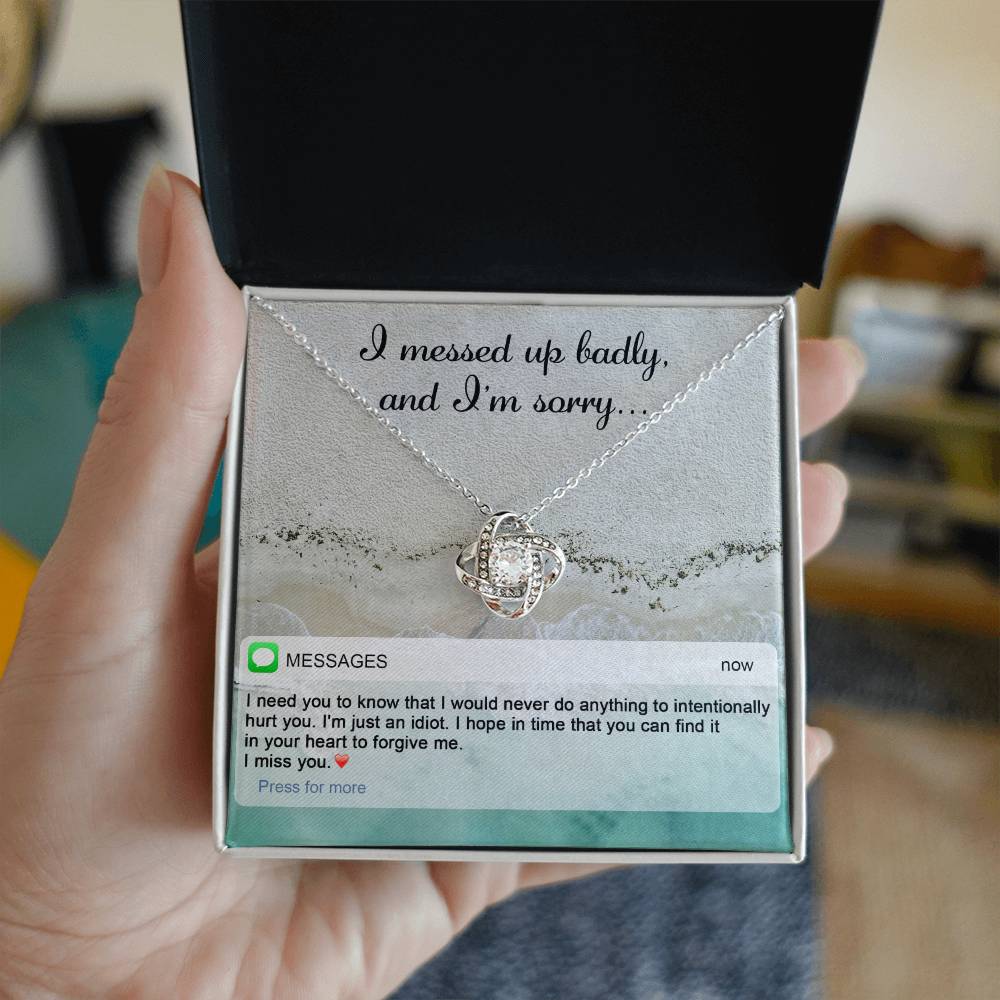 The "Sorry-Just An Idiot - Love Knot Necklace" features a heart-shaped pendant adorned with cubic zirconia crystals, presented on a card inscribed with "I messed up badly, and I'm sorry." It comes complete with a heartfelt text message expressing deep remorse and seeking forgiveness.