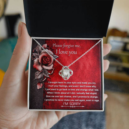 The "Sorry-One Last Chance - Love Knot Necklace" showcases an interlocking design and is elegantly displayed on a card featuring an apology message and images of red roses. Decorated with shimmering cubic zirconia crystals, this personalized gift is set against a red background with black floral accents.