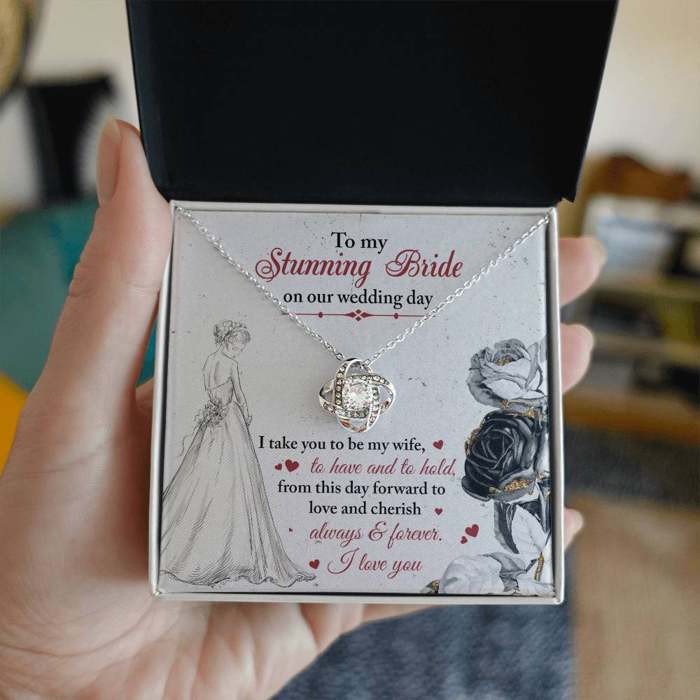 A To My Bride, Be My Wife - Love Knot Necklace with a pendant adorned in cubic zirconia crystals is displayed against a background featuring a bride illustration and a heartfelt wedding message.