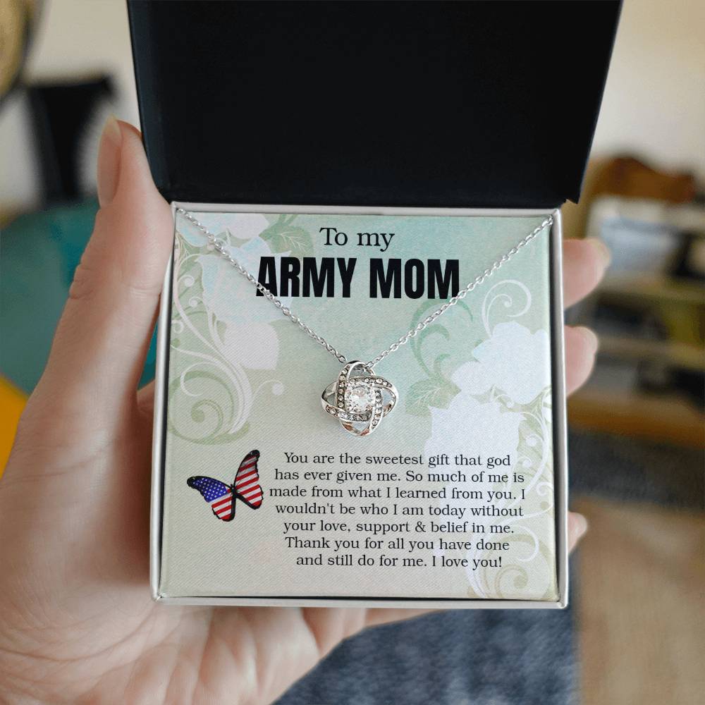 A hand is holding an open jewelry gift box that contains a silver ShineOn Fulfillment Love Knot Necklace with adjustable chain and cubic zirconia crystals, and the box has a message inscribed for an "army mom