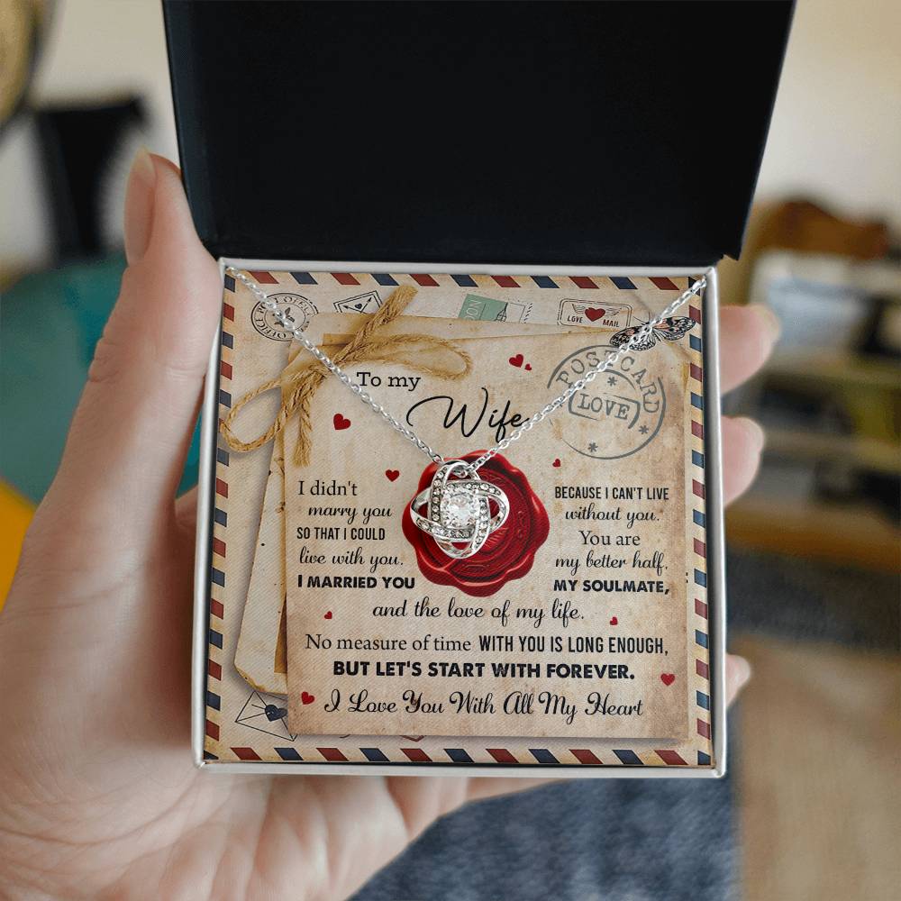 A "To Wife, Marry You - Love Knot Necklace" with an interlocking rings pendant, adorned with cubic zirconia crystals, displayed in a box featuring the background design of a love letter. The letter includes heartfelt messages for a wife, expressing love and commitment—a perfect personalized gift.