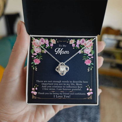 A hand holding a gift box with a To My Mom, Thank yOU For Being My Friend - Love Knot Necklace adorned with cubic zirconia and a heartfelt message for a mother by ShineOn Fulfillment.