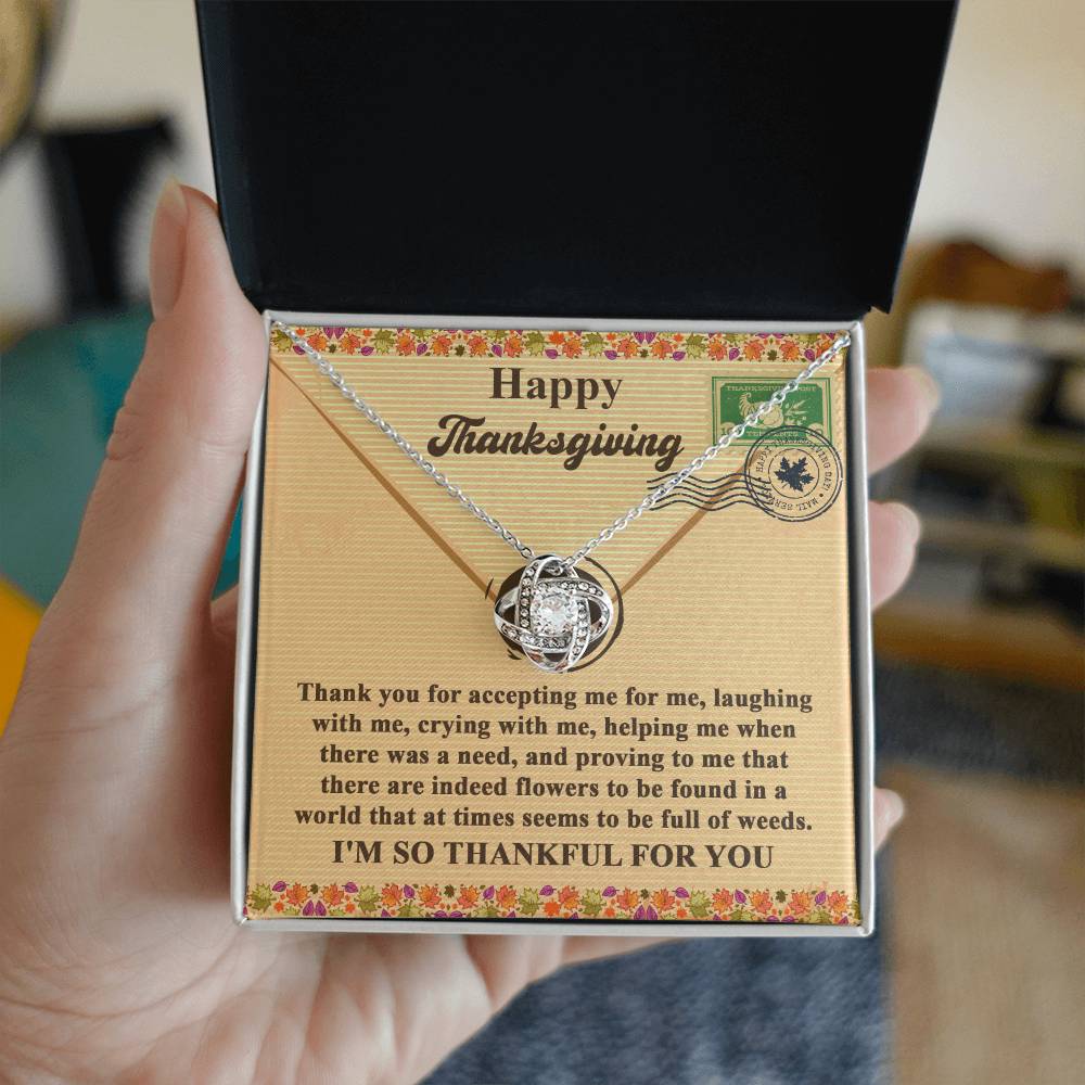 Close-up of a person holding a necklace gift box with the Thanksgiving-Proving To Me message and a floral design inside, showcasing the Love Knot Necklace in white gold finish adorned with cubic zirconia.