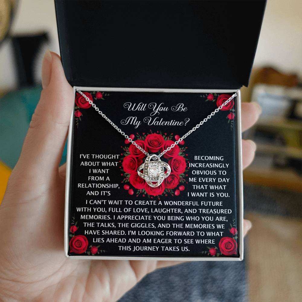 The Soulmate-What I Want - Love Knot Necklace showcases a silver heart pendant with sparkling Cubic Zirconia stones and a Valentine's Day message. It's elegantly packaged in a black box featuring a red rose design, making it an unforgettable gift.