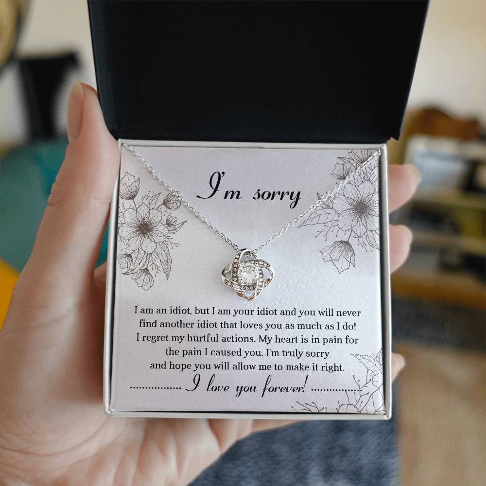 The Sorry-For The Pain - Love Knot Necklace is a personalized gift featuring a love knot pendant adorned with cubic zirconia crystals, presented on a card with an apology message expressing regret and a heartfelt plea for forgiveness, ending with "I love you forever!