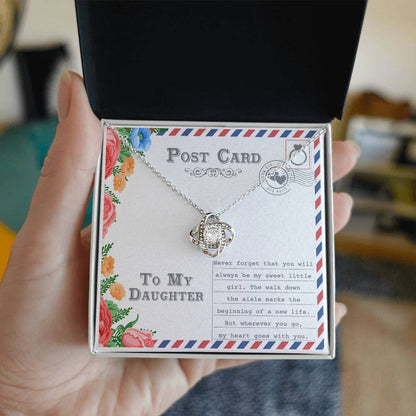 The "To Daughter, Goes With You - Love Knot Necklace," featuring an intertwining design with a gold finish and adorned with cubic zirconia crystals, is displayed on a postcard that reads "To My Daughter." The message includes a heartfelt note about your daughter's wedding and a mother's enduring love.