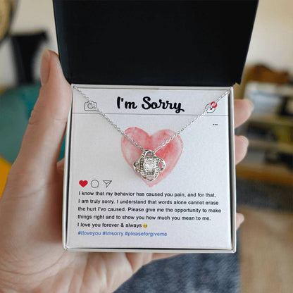 The Sorry-Cannot Erase - Love Knot Necklace, adorned with cubic zirconia crystals, sits on a card featuring an apology message, a pink heart illustration, and hashtags #Iloveyou, #Imsorry, and #pleaseforgiveme.