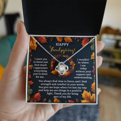 A hand displays an open box containing the Thanksgiving-Lost My Way - Love Knot Necklace, embellished with cubic zirconia crystals. The background card conveys a Thanksgiving message of gratitude and appreciation, perfectly enhancing the necklace's elegance available in either a white gold or yellow gold finish.