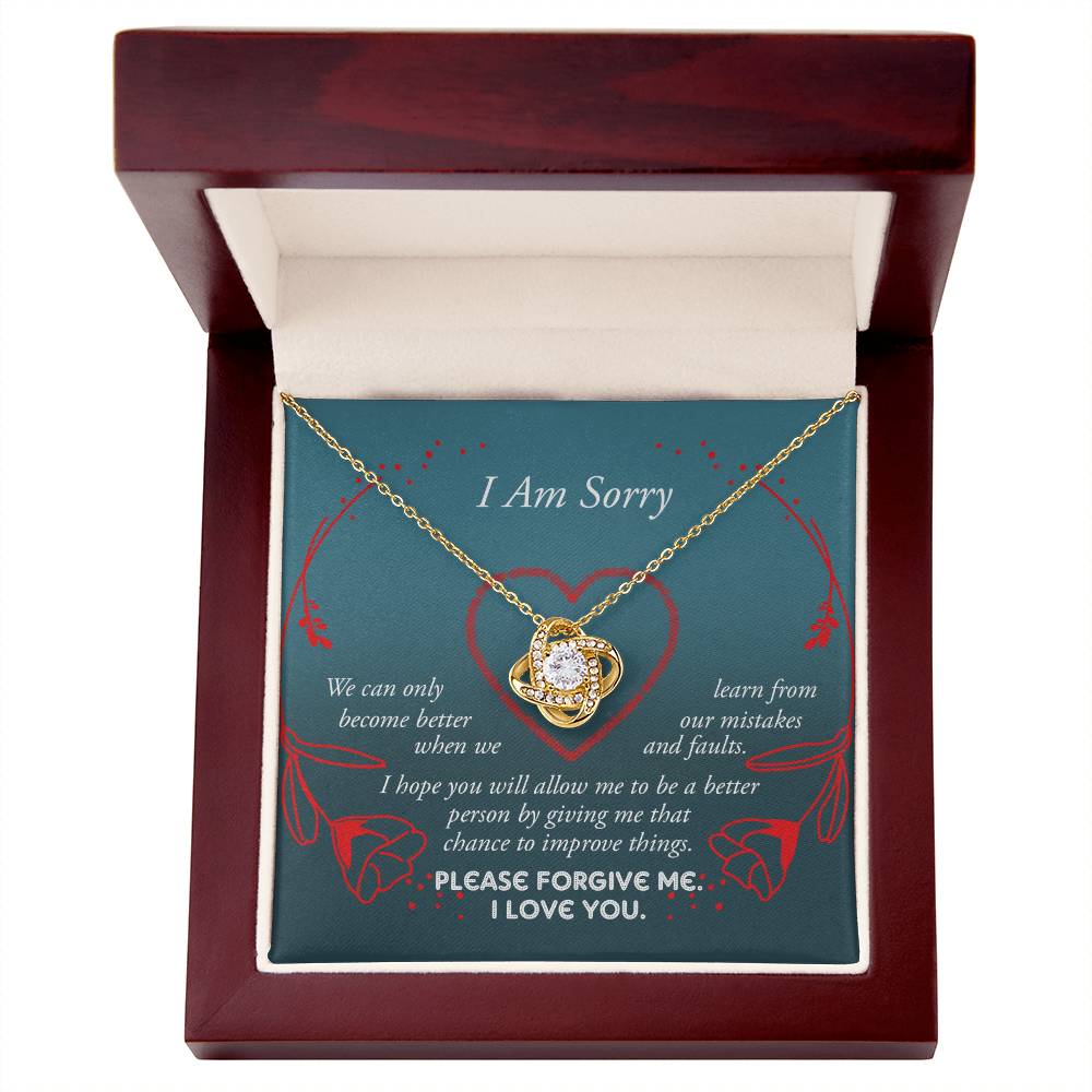 The Sorry-Mistakes And Faults - Love Knot Necklace, featuring a heart-shaped pendant with sparkling cubic zirconia set in white gold, is elegantly presented in a box adorned with the words "I Am Sorry" and a heartfelt apology message.