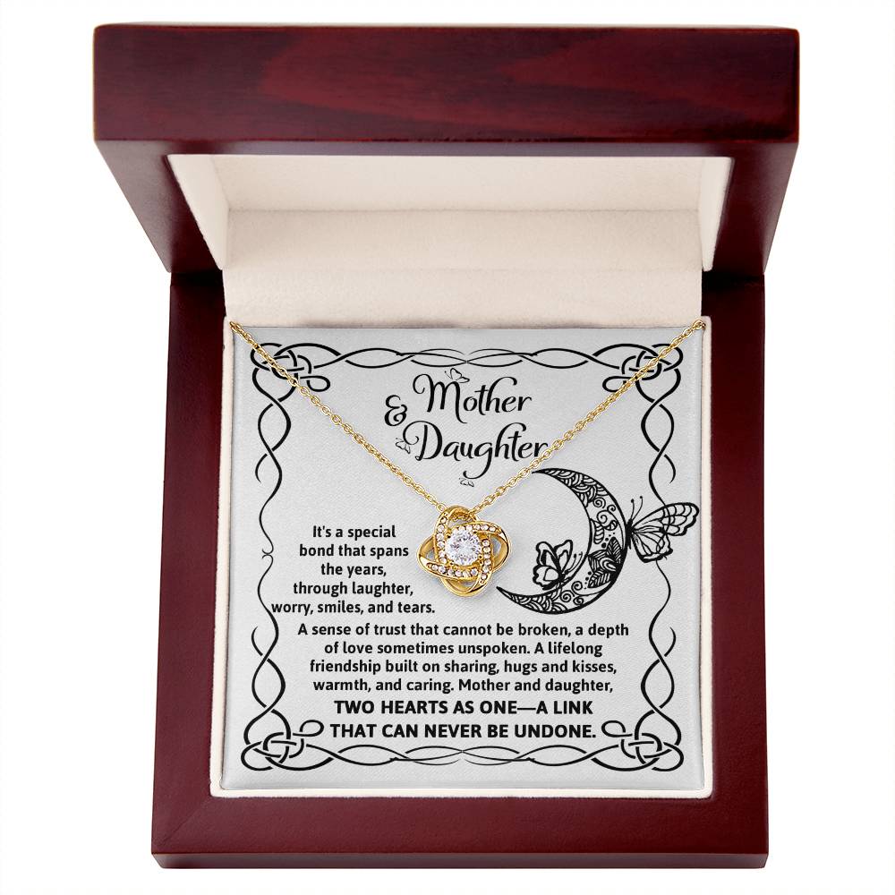 A silver To Daughter, A Special Bond - Love Knot Necklace with an intertwined knot pendant adorned with cubic zirconia crystals, presented on a card with "Mother & Daughter" text, a decorative border, and a heartfelt message about their unbreakable bond.