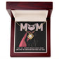 The Mom-An Awesome Mother - Love Knot Necklace, featuring a central gemstone and cubic zirconia crystals, is elegantly presented in an open box. The box illustration shows a masked figure with a cape and the message: "Not All Heroes Wear Capes, Some Become an Awesome Mother Like You," with "MOM" in bold.