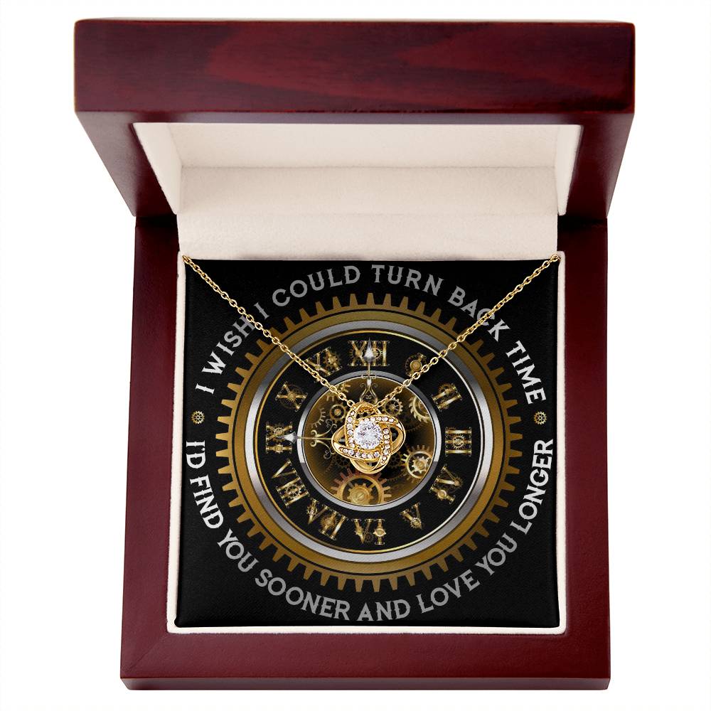 The "To Wife, Turn Back Time - Love Knot Necklace," adorned with cubic zirconia crystals, is elegantly displayed against a clock design backdrop. The text around the clock reads, "I WISH I COULD TURN BACK TIME, I'D FIND YOU SOONER AND LOVE YOU LONGER.