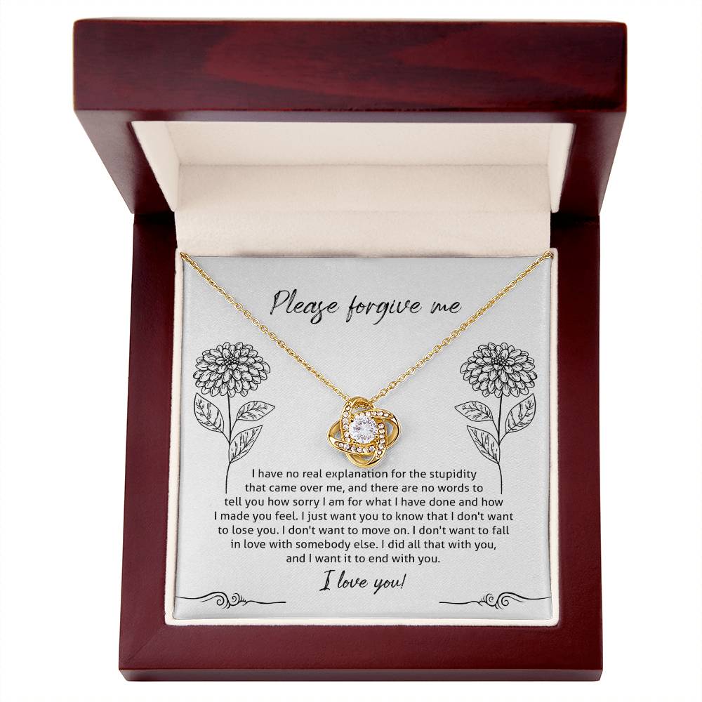 The Sorry-Real Explanation - Love Knot Necklace features an intertwined heart pendant adorned with cubic zirconia crystals, presented in a box. The box lid includes an apology note with floral illustrations, expressing regret, love, and a plea for forgiveness.