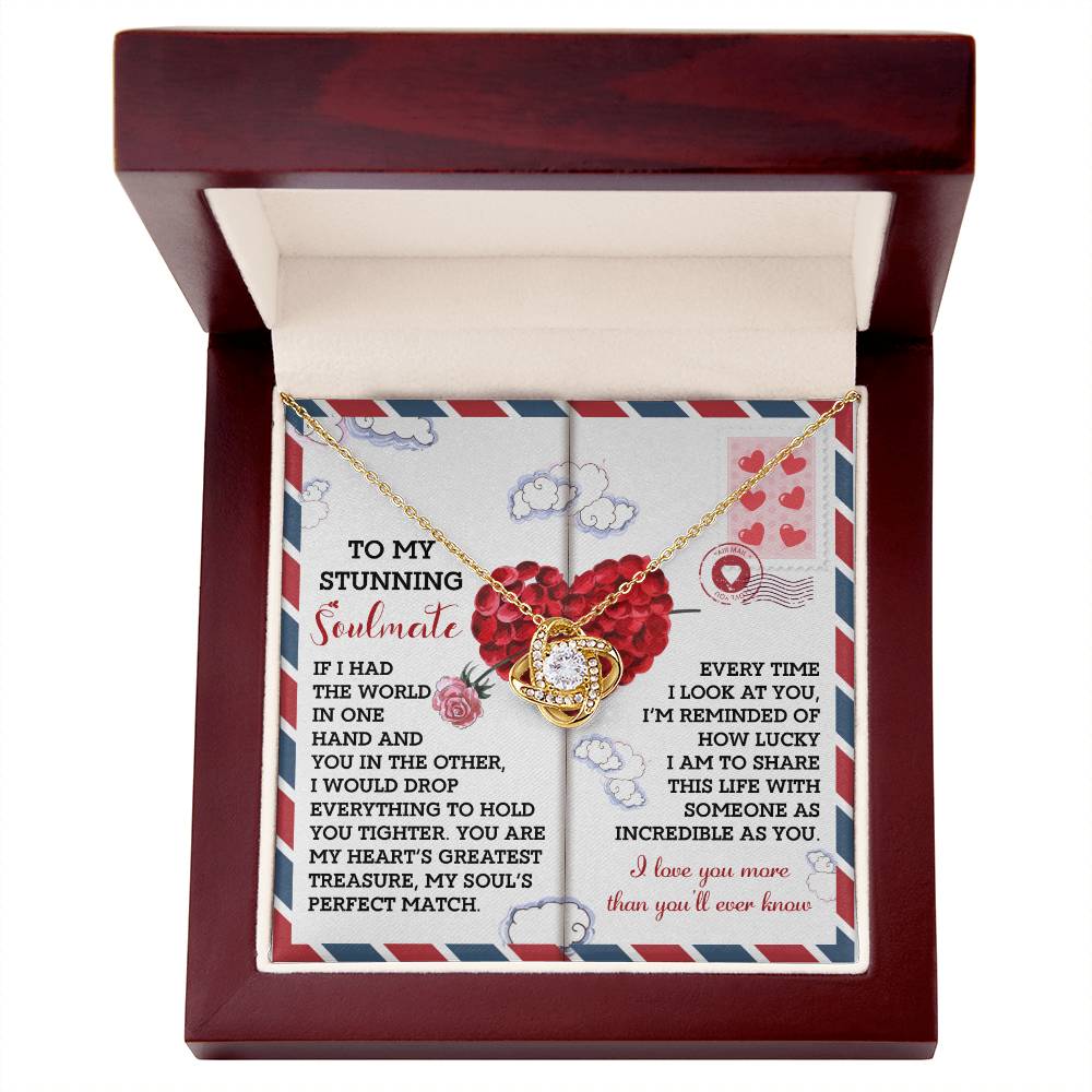 The Soulmate-Perfect Match Love Knot Necklace features a circular pendant adorned with cubic zirconia crystals, displayed in an open red-lined box. The decorative card with romantic text and heart designs adds a personalized touch, making it an ideal gift for someone special.