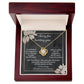 The Sorry-Lies In Yours - Love Knot Necklace, a stunning piece embellished with cubic zirconia crystals, is showcased against a dark-themed backdrop adorned with floral designs. The background beautifully conveys an apology message infused with love and regret.