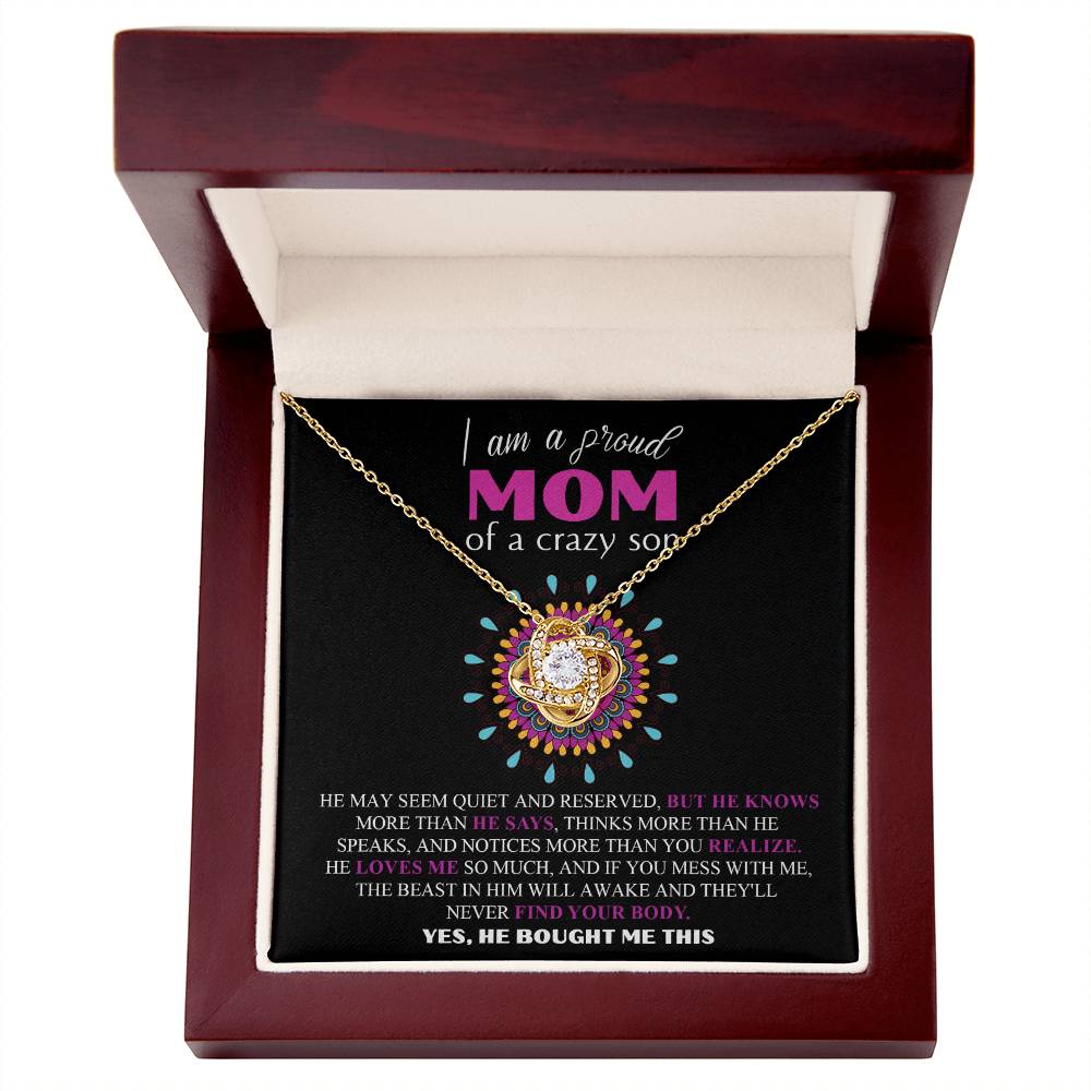 Encased elegantly in an open wooden display, the To Mom, Proud Mom - Love Knot Necklace features stunning 14k white gold craftsmanship and beautiful cubic zirconia crystals. It also includes a decorative card inscribed with "I am a proud MOM of a crazy son" along with a heartwarming quote highlighting the son's protective nature.