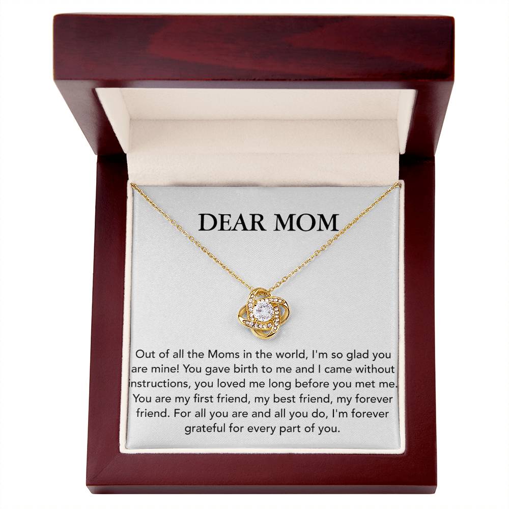 A gold Dear Mom, Out of All The Moms In The World - Love Knot Necklace with a circular pendant, adorned with Cubic Zirconia Crystals, is displayed in a red jewelry box with a message to "dear mom" on the inside lid by ShineOn Fulfillment.