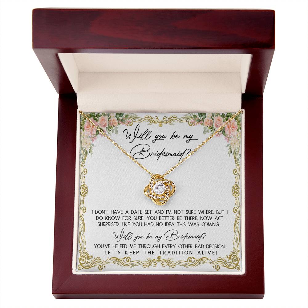 A To Bridesmaid, Keep The Tradition - Love Knot Necklace in a gift box with floral accents, featuring 14k white gold and cubic zirconia crystals. The message reads: "Will you be my Bridesmaid? I don't have a date set... act surprised. You've helped me through every other bad decision. Let's keep the tradition alive!