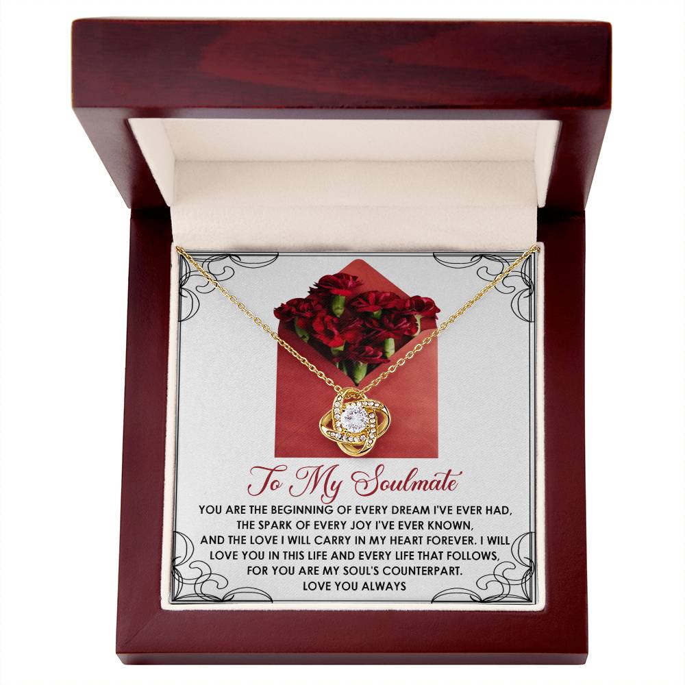 The Soulmate-My Heart Forever Love Knot Necklace, embellished with cubic zirconia crystals, features a central gem in a decorative box. The inscription expresses love to a soulmate, set against red roses—a perfect personalized gift.