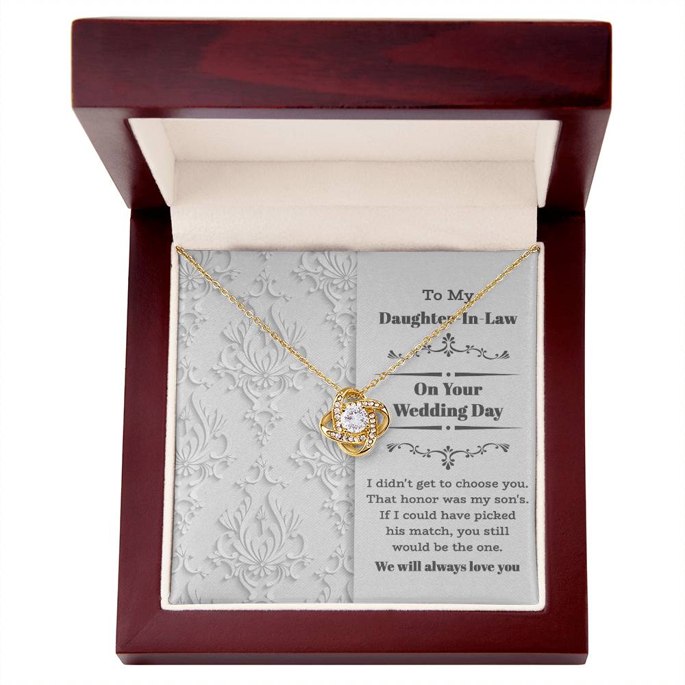 To My Daughter-In-Law Wedding, Be The One - Love Knot Necklace with an intertwined heart design, adorned with cubic zirconia crystals, displayed on a decorative backing card. The card reads: "To My Daughter-In-Law On Your Wedding Day" with a sentimental message below. Perfect as a gift for a loved one.