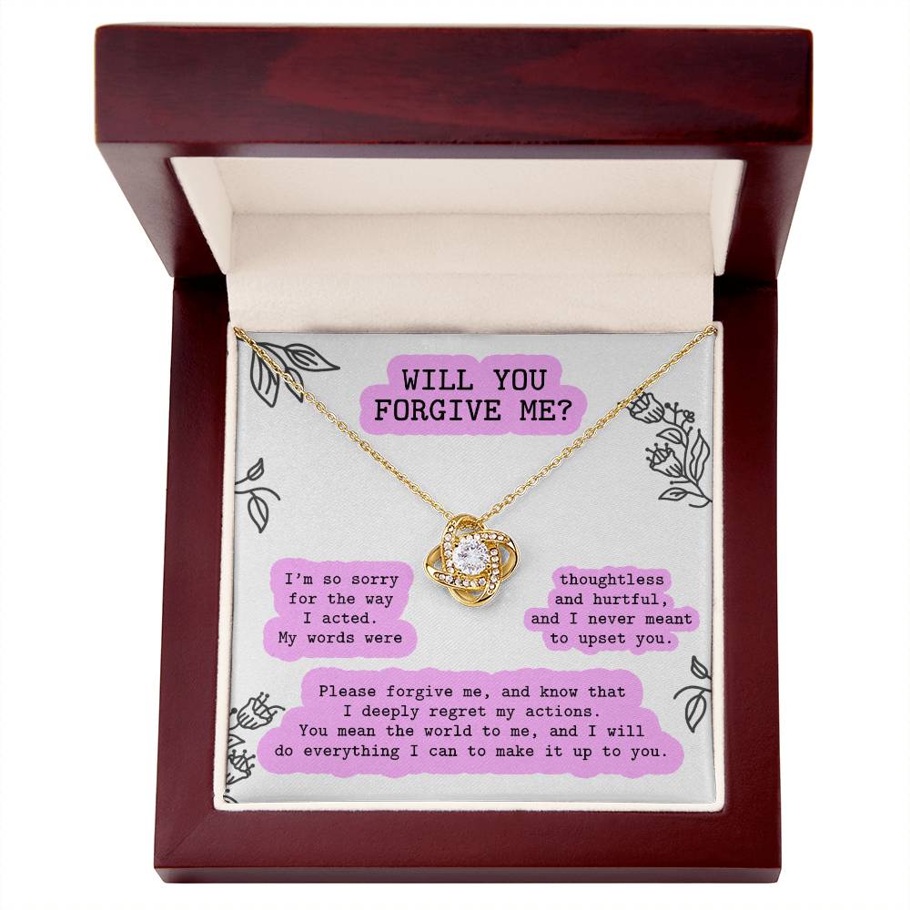 The Sorry-Never Meant To - Love Knot Necklace, with a gold finish, is nestled in a wooden box. The interior bears a heartfelt message: "Will you forgive me?" alongside an apology note adorned with floral designs. The pendant sparkles with premium cubic zirconia crystals, adding an extra touch of elegance to the sincere gesture.