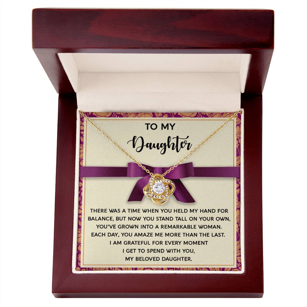 Introducing the Daughter-Spend With You Love Knot Necklace, featuring a beautifully adorned pendant in a wooden box with a heartfelt message for your daughter, expressing pride and love. The pendant is embellished with sparkling cubic zirconia crystals and presented with a purple ribbon. Choose either a white gold or yellow gold finish for an extra touch of elegance.