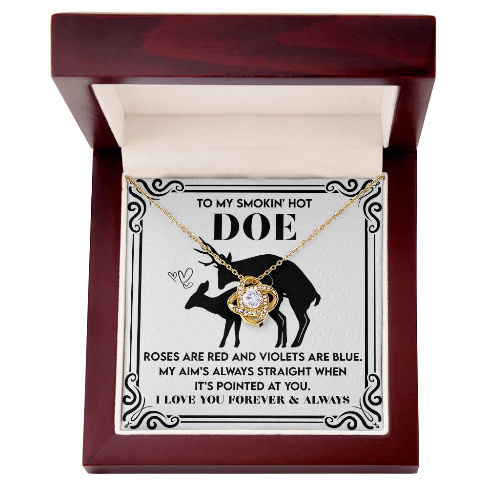 The Soulmate-Pointed At You Love Knot Necklace, adorned with cubic zirconia, sits in an open box with a deer silhouette. The message begins, "To my smokin' hot doe. Roses are red and violets are blue..." It's the perfect gift for your loved one.