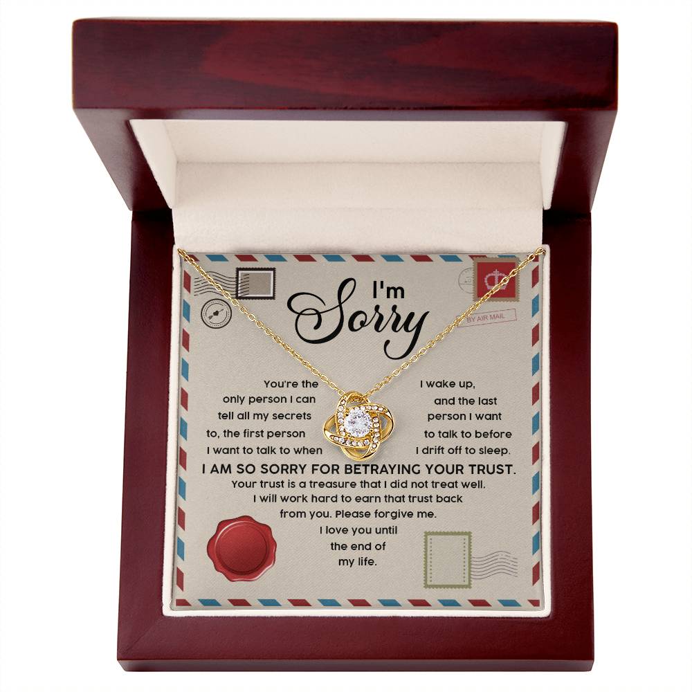 This "Sorry-The Only - Love Knot Necklace" features a circular pendant and is presented in a red wooden box. Made from 14k white gold over stainless steel, the necklace sparkles with cubic zirconia crystals. Inside, you'll find a heartfelt message that reads: "I’m Sorry. I am so sorry for betraying your trust," followed by an apologetic text.