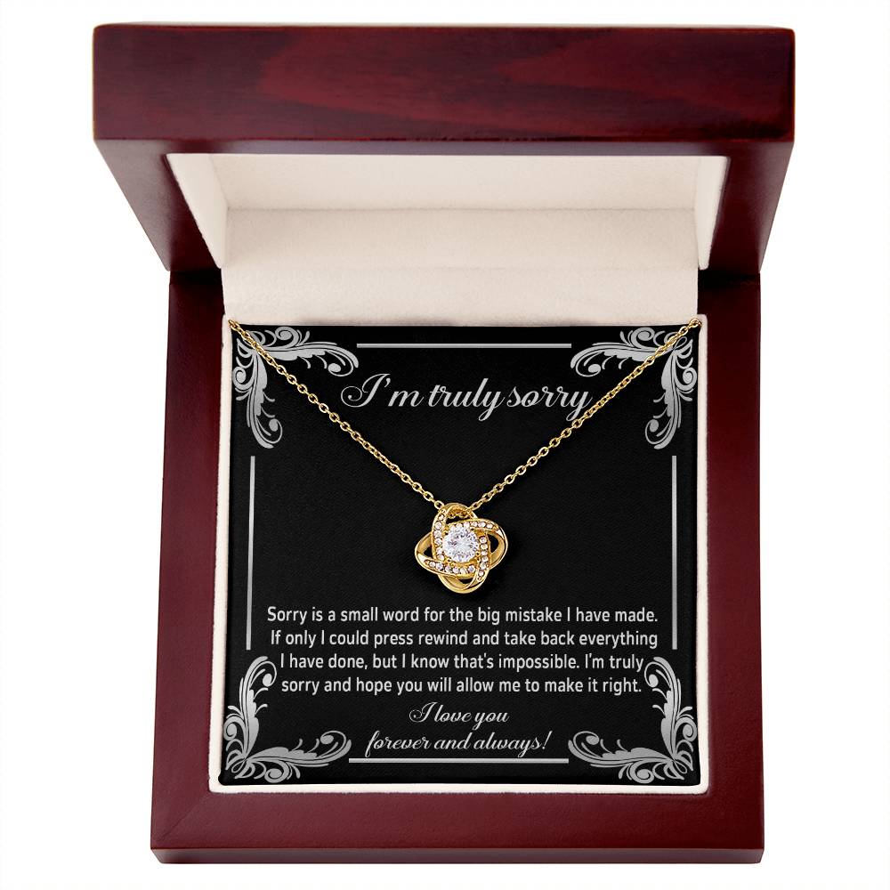 The "Sorry, Make It Right 2 - Love Knot Necklace" showcases a silver interlinked design on a black background. The backdrop features an apology message written in white text, complemented by the brilliance of cubic zirconia crystals.