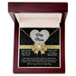 The Dog Mom-In Every Way - Love Knot Necklace comes in a decorative box that features a gold-finished necklace with a white floral pendant. The box has "Dog Mom" on a heart and includes a message thanking her for love and care, with a playful nod to dog antics sparkling like cubic zirconia crystals.