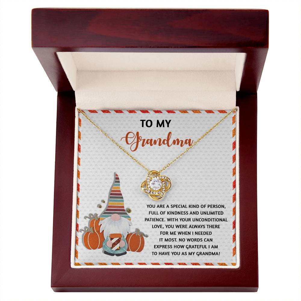 A personalized gift awaits, featuring the Grandma-Needed It Most - Love Knot Necklace elegantly placed in a wooden box. Embellished with dazzling cubic zirconia, it includes a card lovingly inscribed "To My Grandma" alongside a charming gnome illustration.