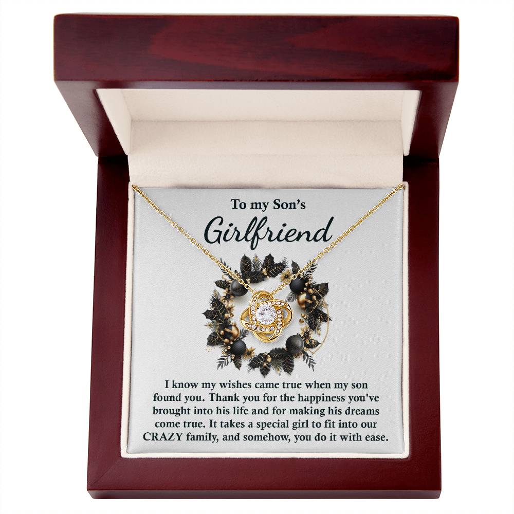 The Son's Girlfriend - Found You - Love Knot Necklace, featuring a floral pendant, is beautifully presented in a wooden box. Engraved with the message "To my Son's Girlfriend," it conveys appreciation and affection, making it an ideal personalized gift.