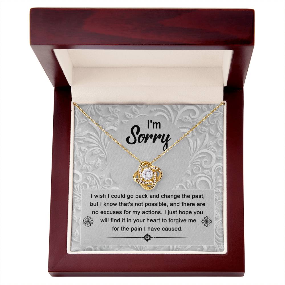 The Sorry-Change The Past - Love Knot Necklace, featuring a gold pendant with a white cubic zirconia crystal, is beautifully presented in an open wooden box. The inside lid bears the words "I'm Sorry," accompanied by an engraved apology message below, making it an ideal personalized gift for a heartfelt apology.