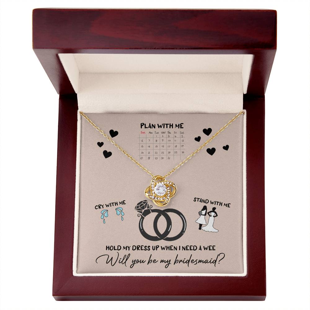 A To Bridesmaid, Will You Be 2 - Love Knot Necklace, adorned with cubic zirconia crystals, is displayed on a card featuring a calendar, wedding rings, and bridesmaid-related illustrations. The text reads, "Will you be my bridesmaid?" Choose from a white gold or yellow gold finish to make the moment even more special.