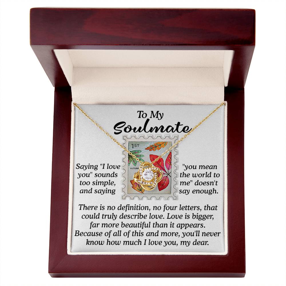 Within a wooden box, the Soulmate-Far More Beautiful - Love Knot Necklace symbolizes an unbreakable bond. The accompanying card is inscribed with "To My Soulmate" and features a poetic expression of love. This necklace is embellished with cubic zirconia crystals and showcases a floral motif surrounding a radiant central gem.