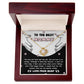 A "To Mom To Be, Two Worlds Collide - Love Knot Necklace" comes in a wooden box. The inscription reads "To the Best Mommy" and includes a heartfelt message about the unbreakable bond between parent and child, adorned with sparkling cubic zirconia crystals.