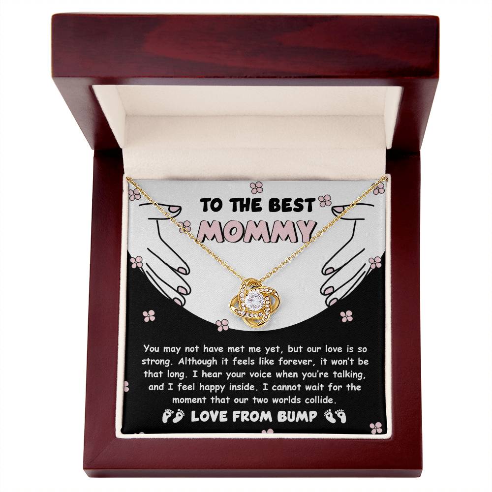 A "To Mom To Be, Two Worlds Collide - Love Knot Necklace" comes in a wooden box. The inscription reads "To the Best Mommy" and includes a heartfelt message about the unbreakable bond between parent and child, adorned with sparkling cubic zirconia crystals.